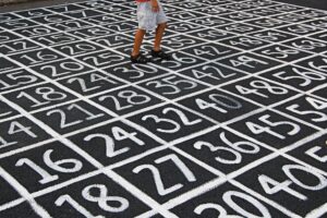An image of the pavement in a school yard with a grid of numbers painted on the ground. 