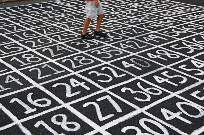A photograph of the pavement in a school yard with a grid of numbers painted on the ground.