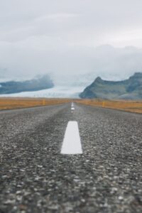 A photograph looking down the center line of a road. The camera is low to the ground so the image has a blurry foreground and sharp area before getting and gets blurry again for the background. The road leads toward a cloud shrouded glacier.  Consider pulling back and developing an IP strategy that accounts for AI and copyright.  