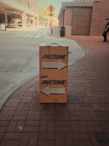 An image of a sign on a sidewalk. An arrow points right with label "Awesome". "Less Awesome" is to the left. We like this kind of feedback on our IP management and assistance. 