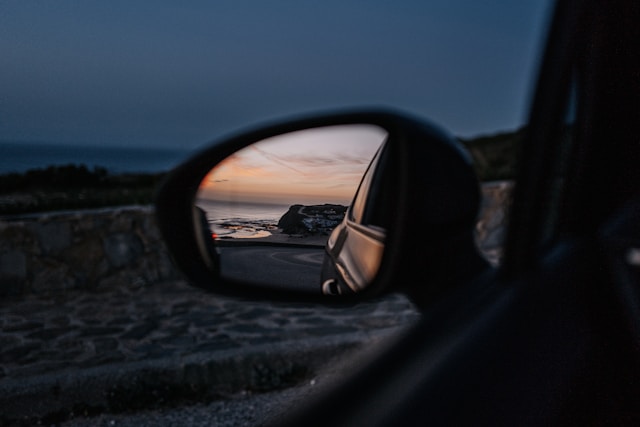An image of a beach in the side mirror of a vehicle.